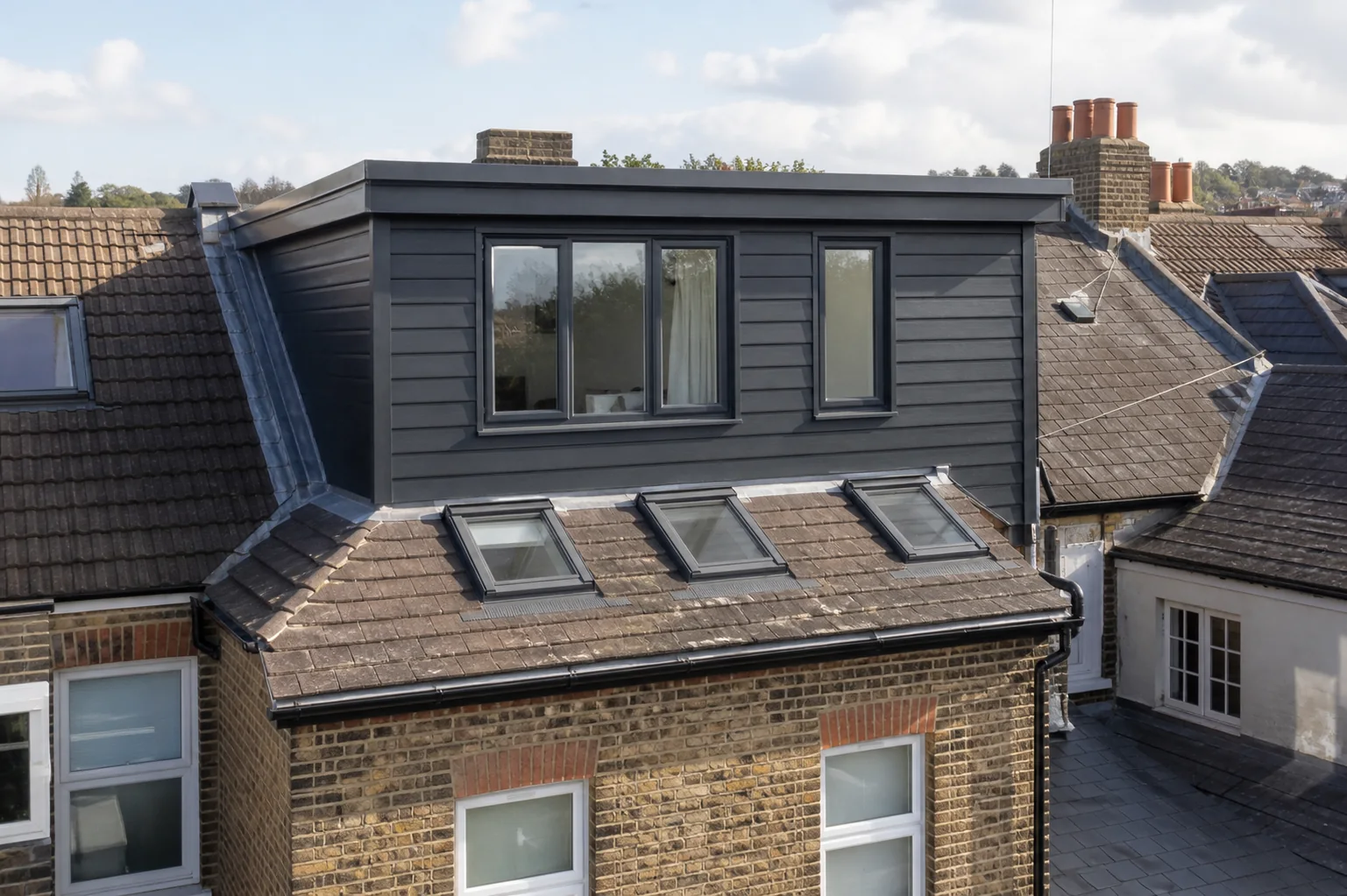 Completed rear dormer loft conversion with dark cladding, roof windows and lead weathering details
